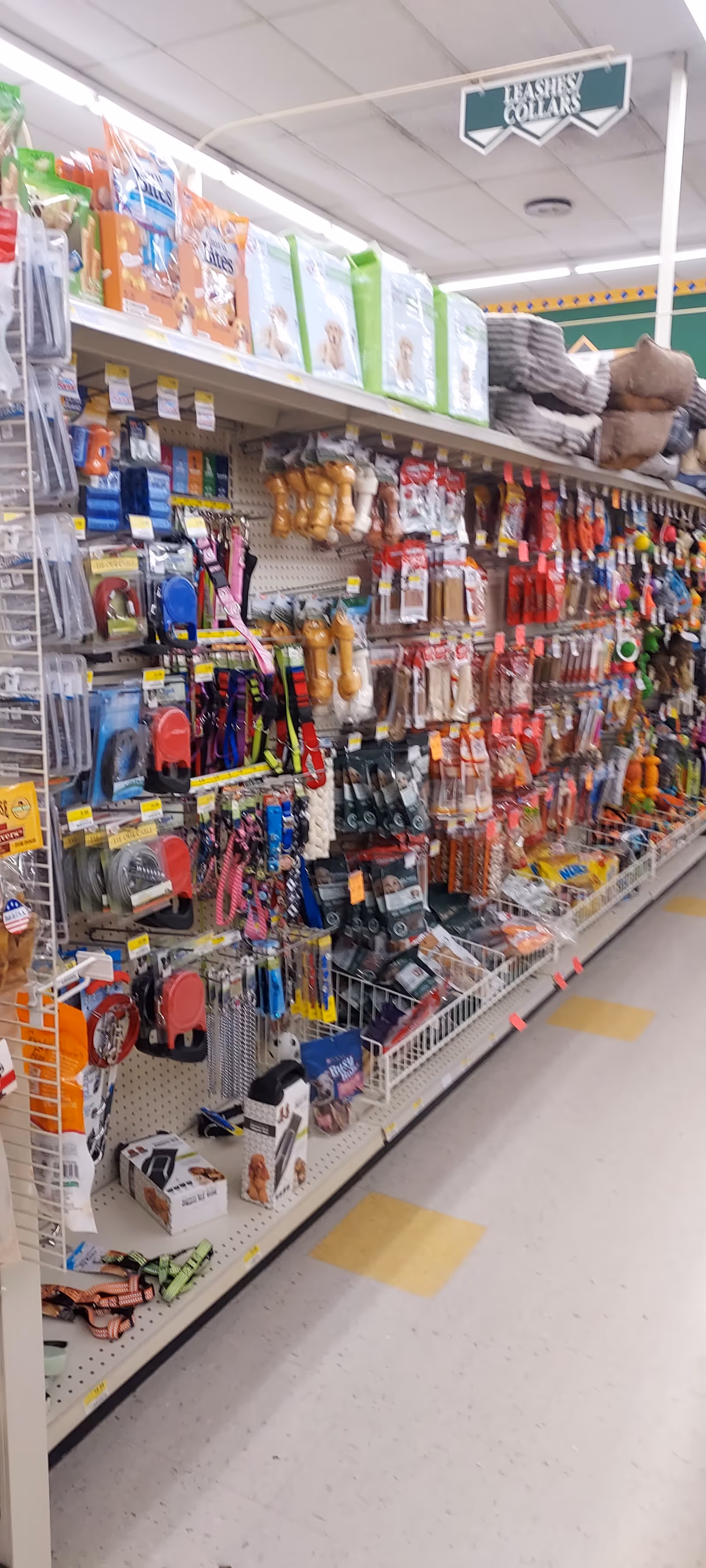 A long aisle in Discount Drug Mart filled with assorted pet supplies and household items.