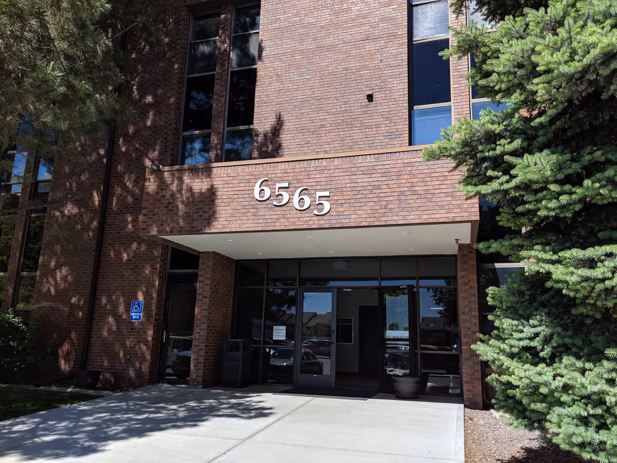 Brick building entrance with large 6565 numbers and glass doors.