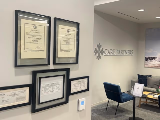 Interior lobby displaying framed certificates and a Care Partners sign beside a seating area.