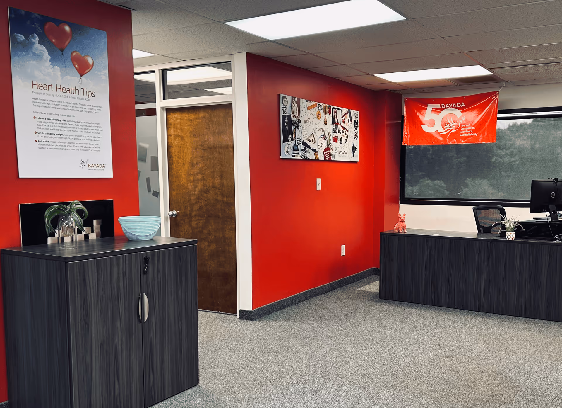 Reception area with red walls, dark desks, and a BAYADA banner.