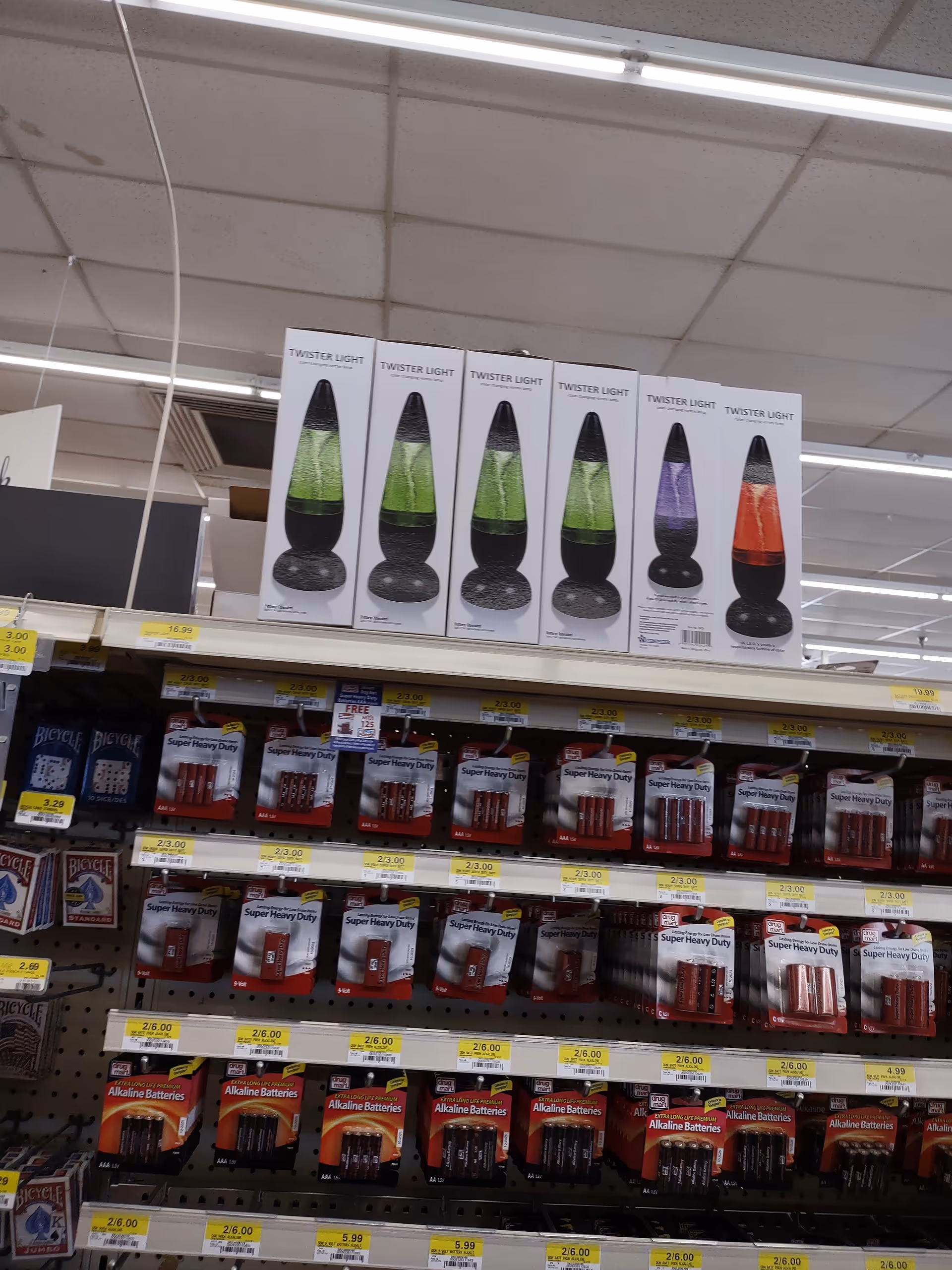 Store aisle with Twister Light lava lamp boxes on the top shelf and batteries below.