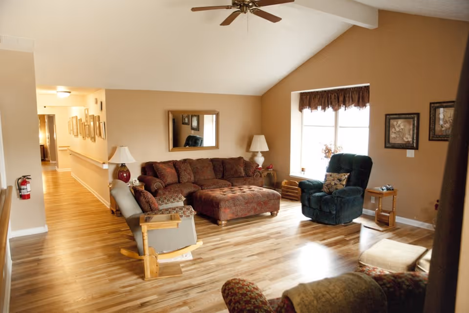 A spacious living room with a brown sectional, recliner, lamps, and a bright window.