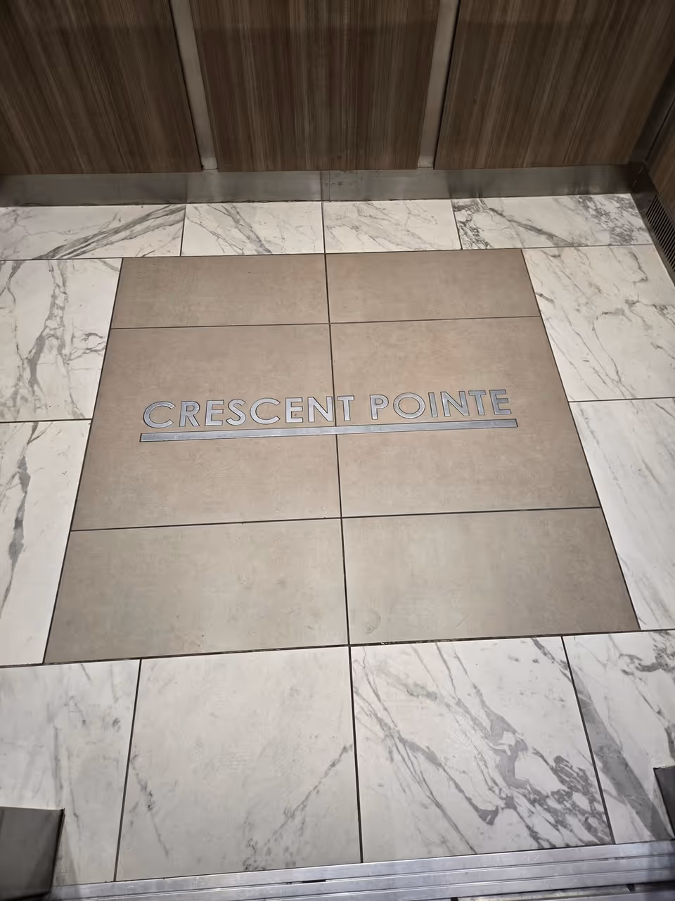 Elevator lobby floor with tiled surface reading Crescent Pointe in marble pattern