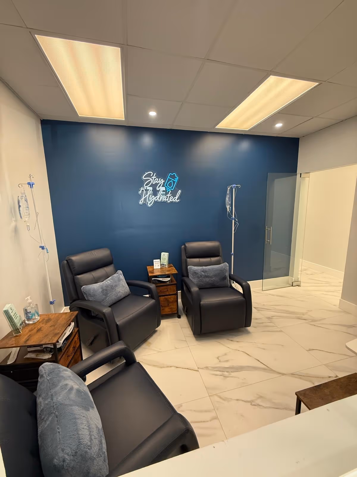 Infusion lounge with black recliners, IV stands, and a blue wall.