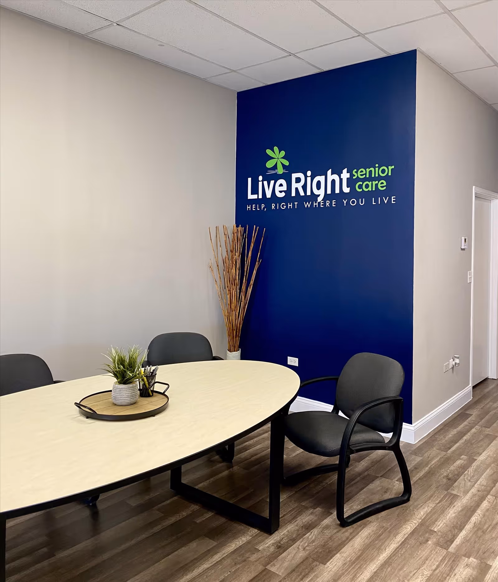 Interior lobby area with a blue Live Right senior care wall sign, round table, and chairs.