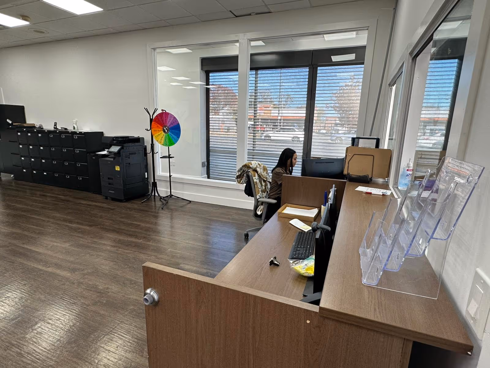 Office reception area with desk, computer, and large windows.