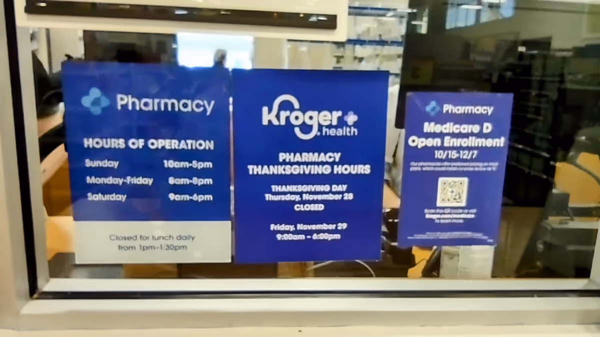 Blue Kroger Pharmacy signs posted on a glass window inside a facility.