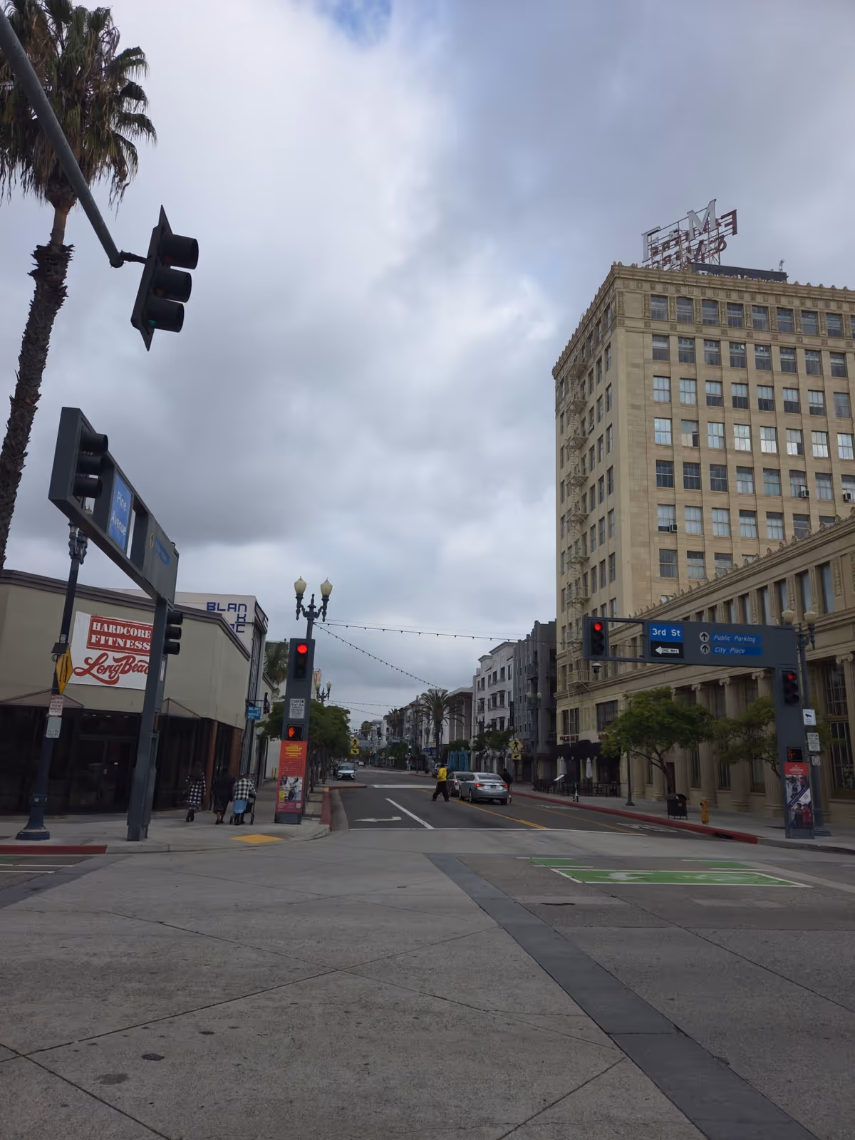 Urban street scene with tall buildings, palm trees, traffic lights, and crosswalks.