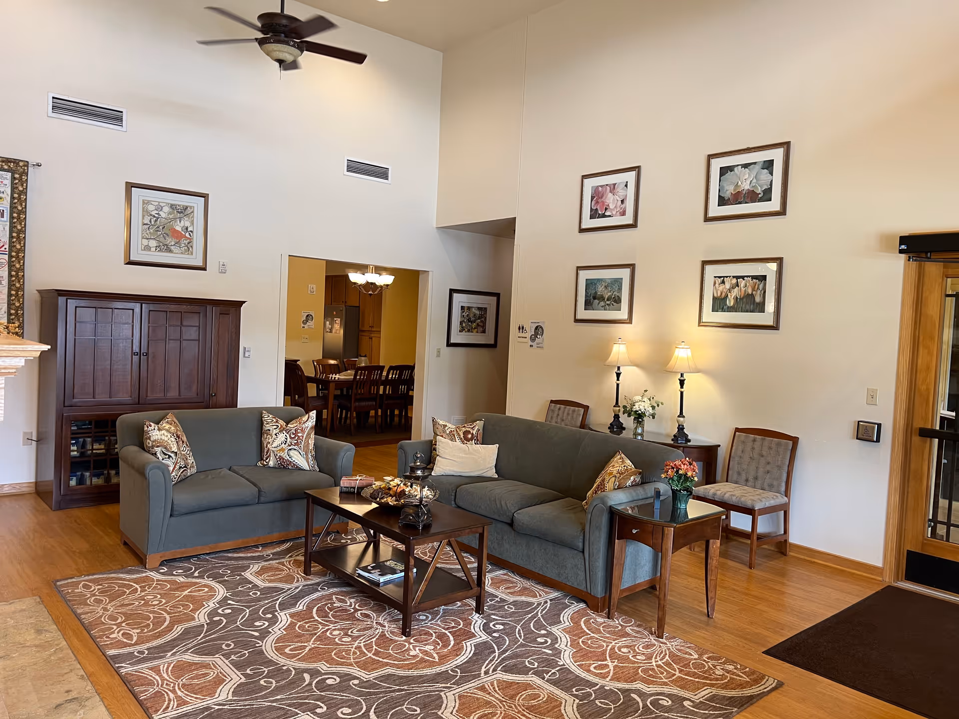 Cozy senior living facility lobby with sofas, coffee table, lamps, and framed artwork.
