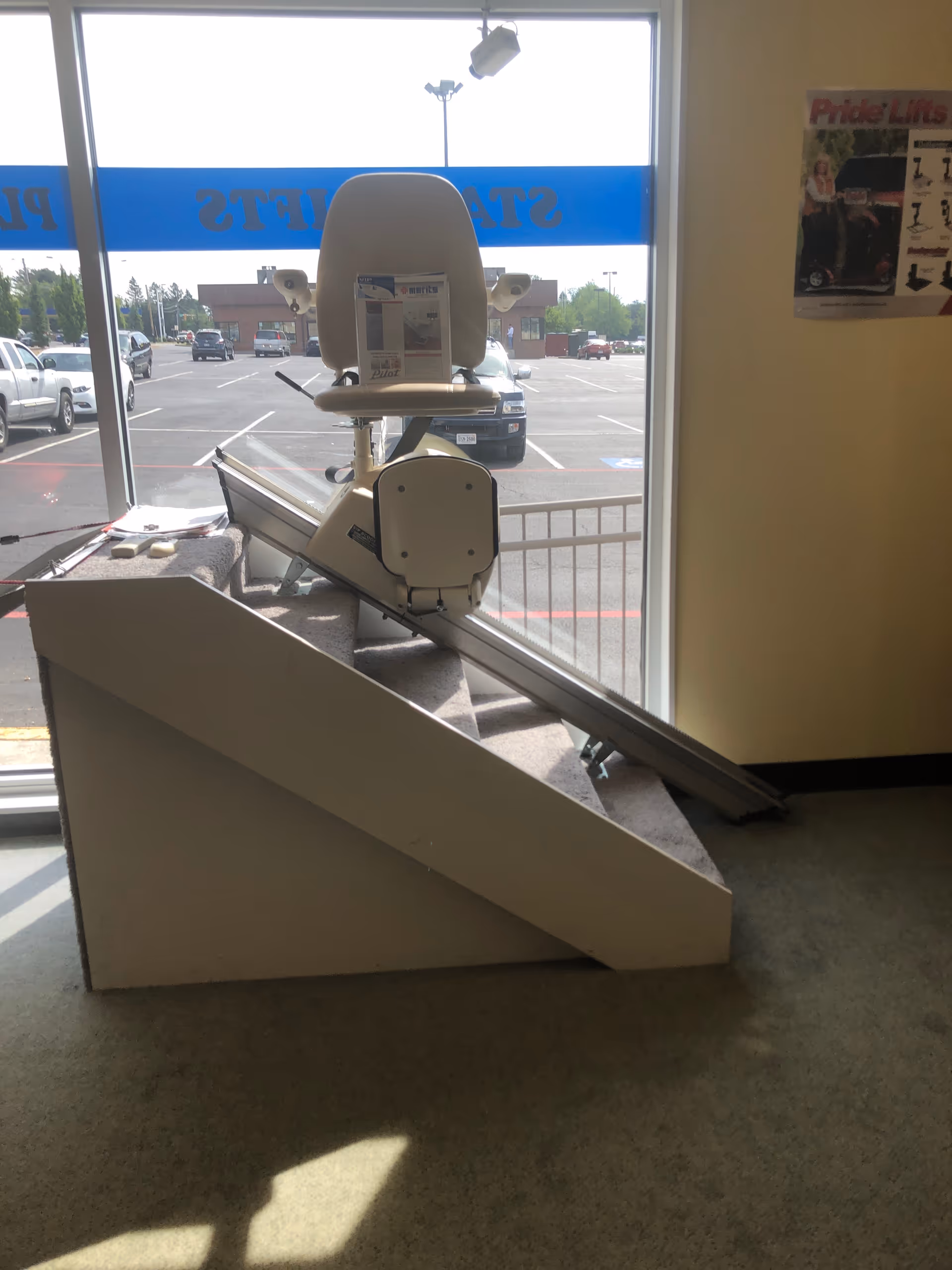 Indoor stair lift chair on a track by a large window in a showroom.
