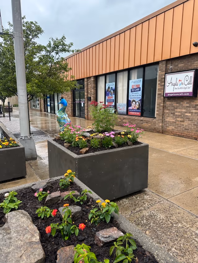 Exterior view of Angels On Call Home Care storefront with flower planters and posters.