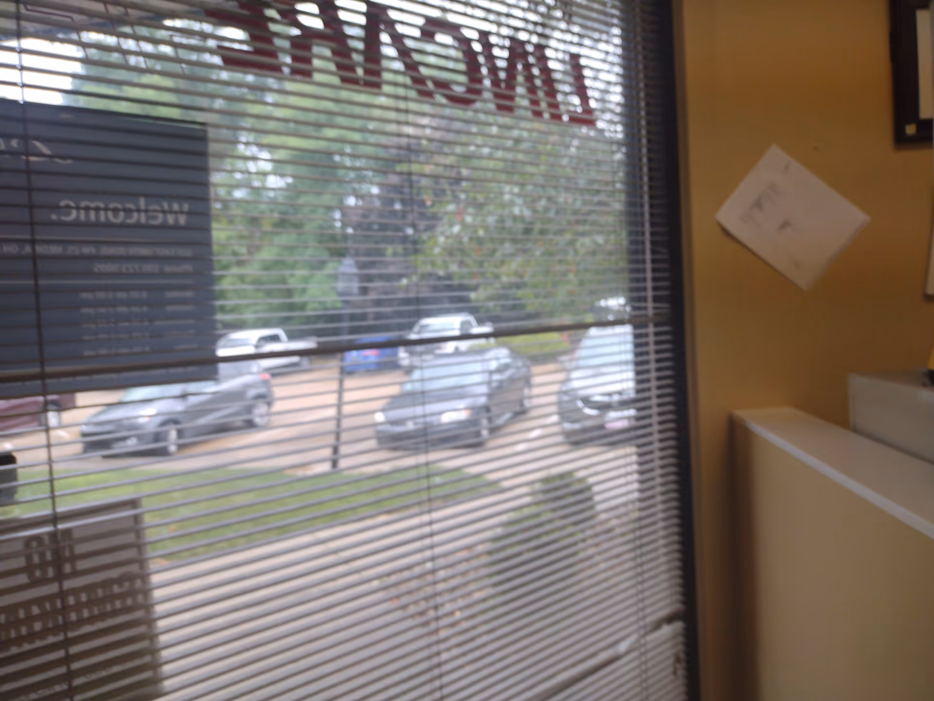 Interior reception area with blinds and a view of parked cars outside.