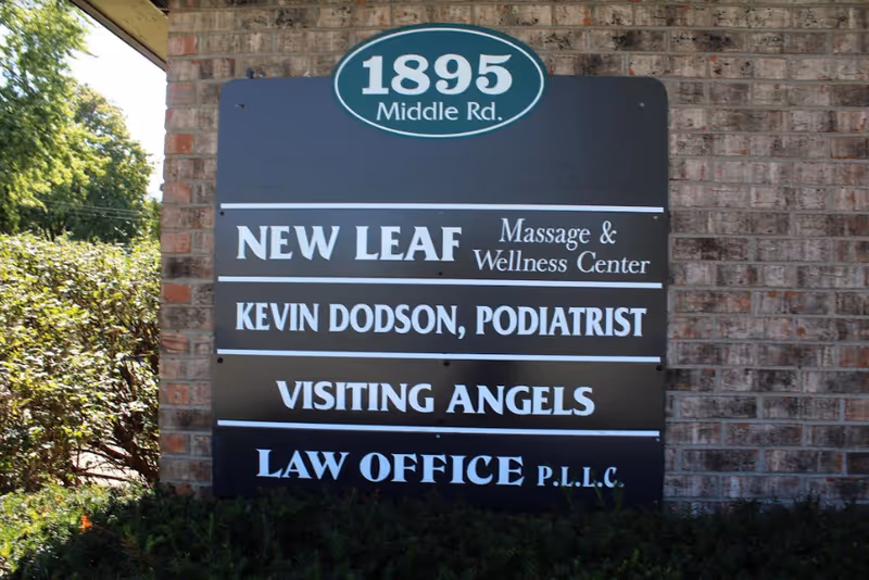 Exterior brick wall signboard listing Visiting Angels among several businesses.