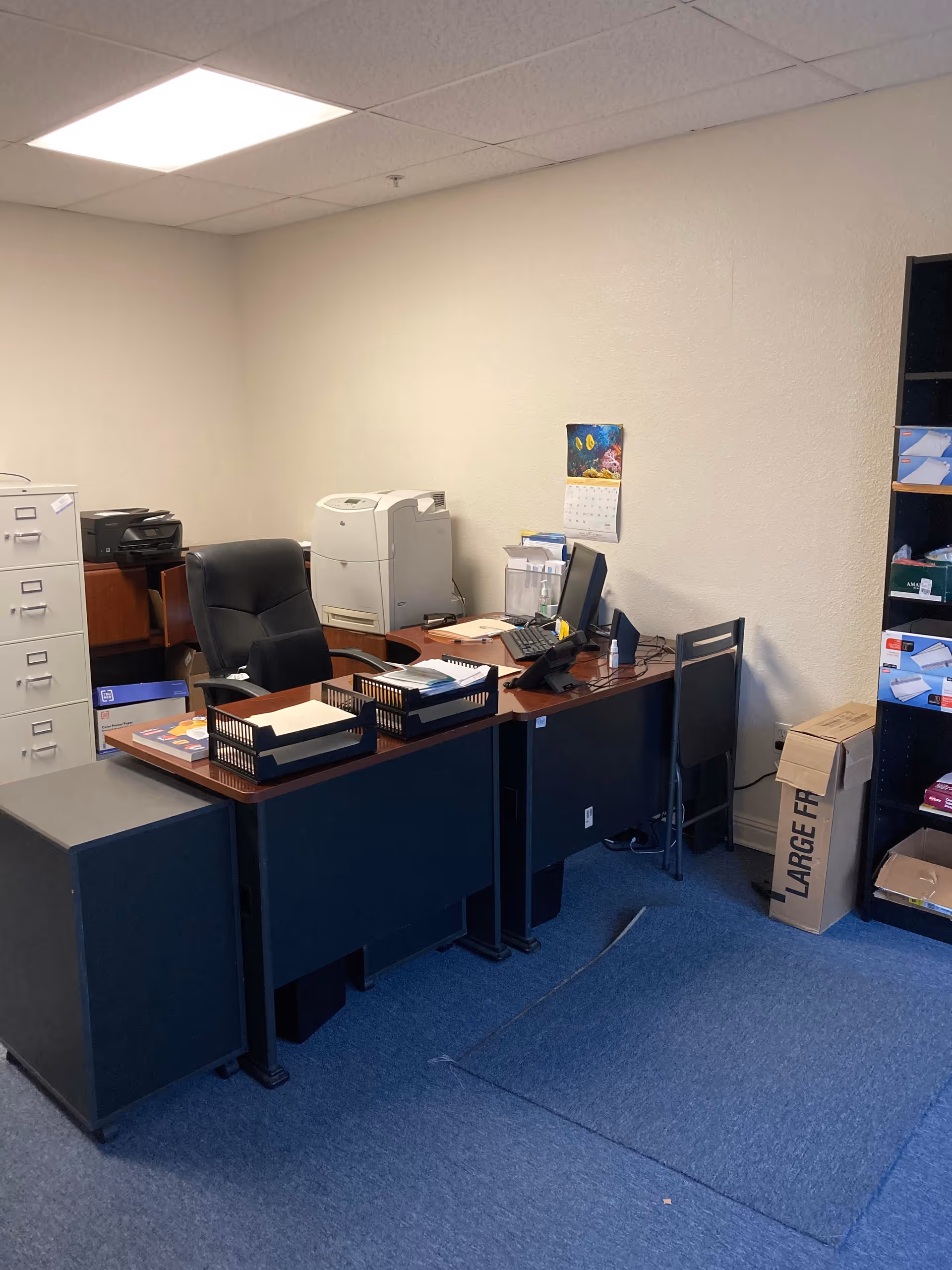 Office workspace with desk, computer, printer, and filing cabinets in a senior facility.