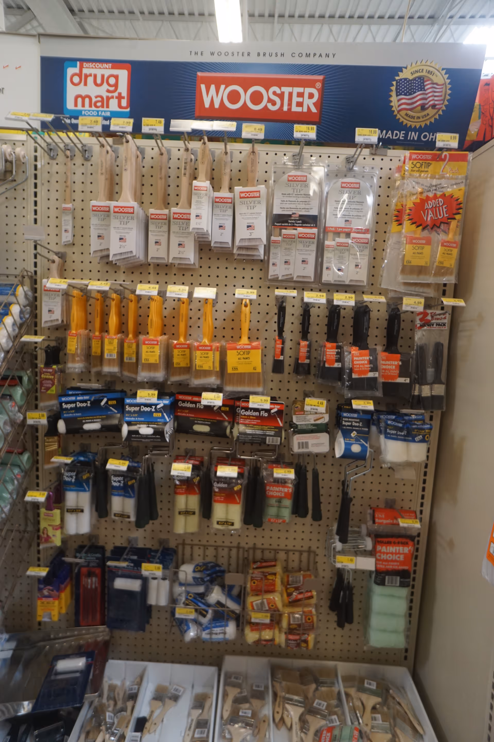 Interior of a Discount Drug Mart display rack with tools and packaging on pegboard.