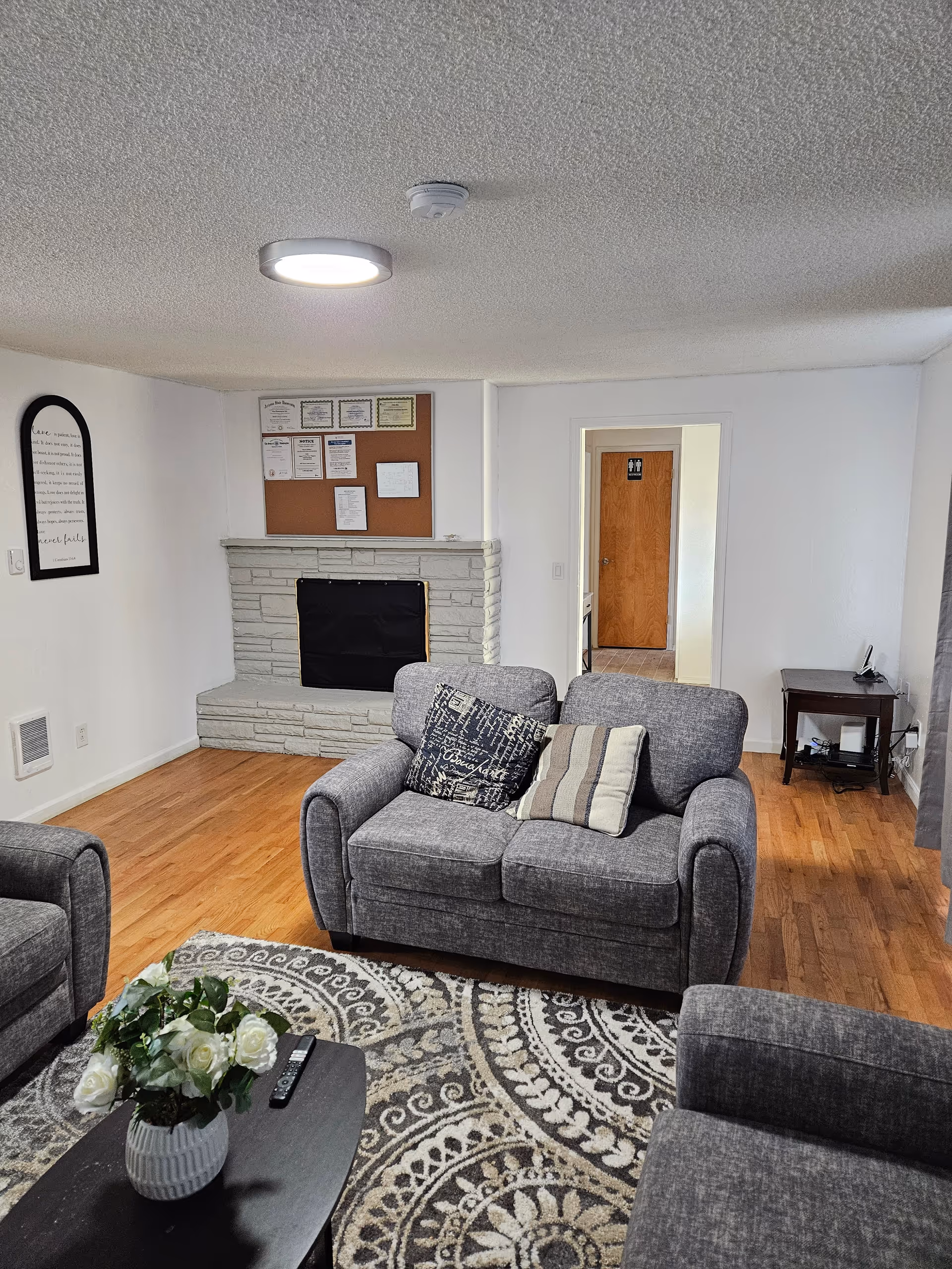 Cozy living room in a senior home with gray sofas, fireplace, and rug.