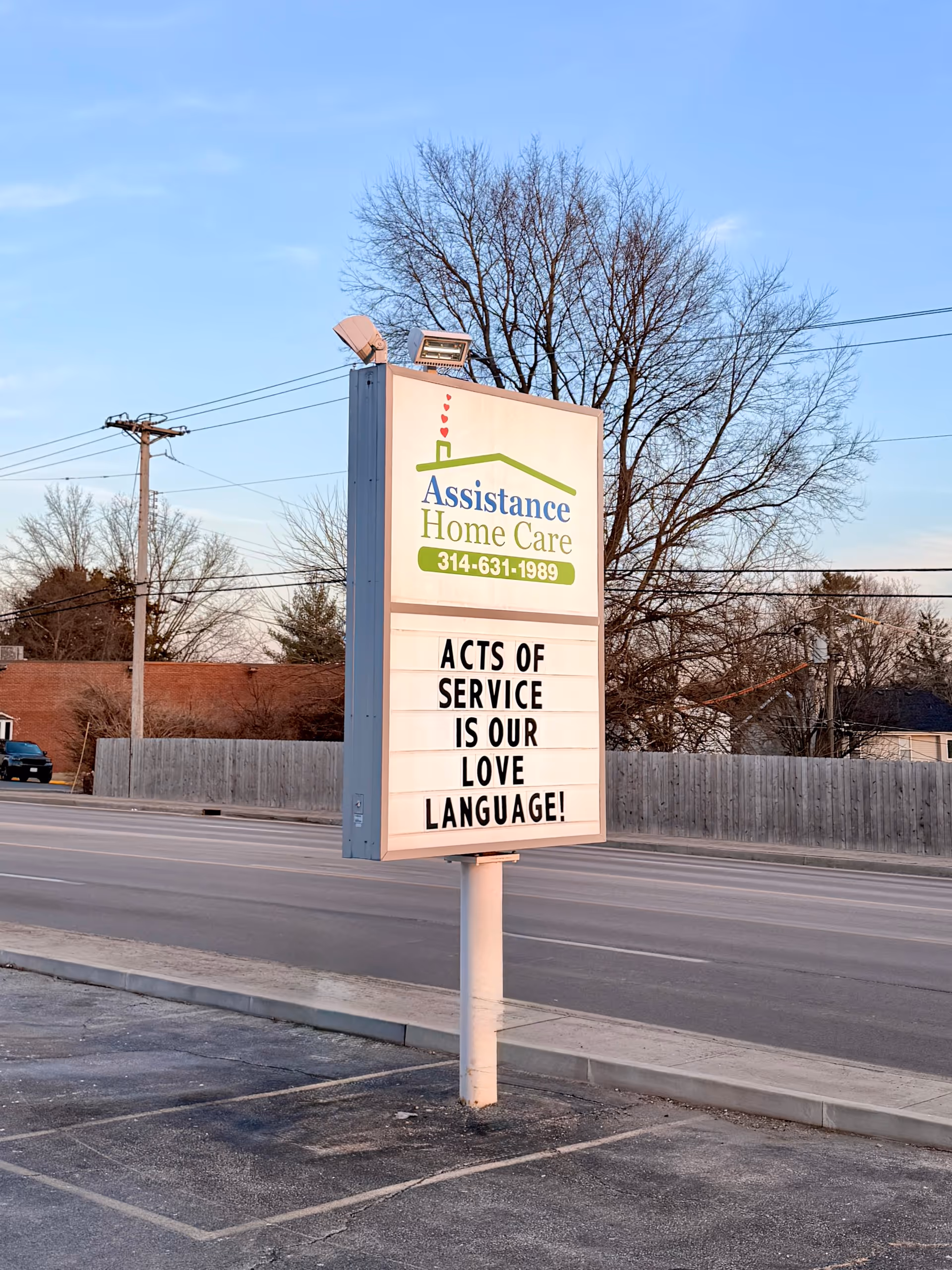 A roadside sign for Assistance Home Care reads Acts of Service is love language.