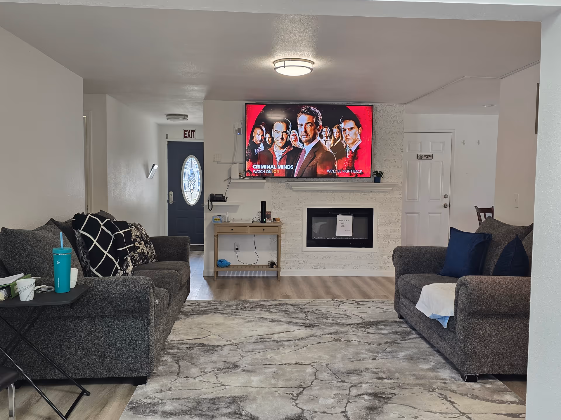 Living room in a senior home with two gray sofas, mounted TV, and a fireplace.