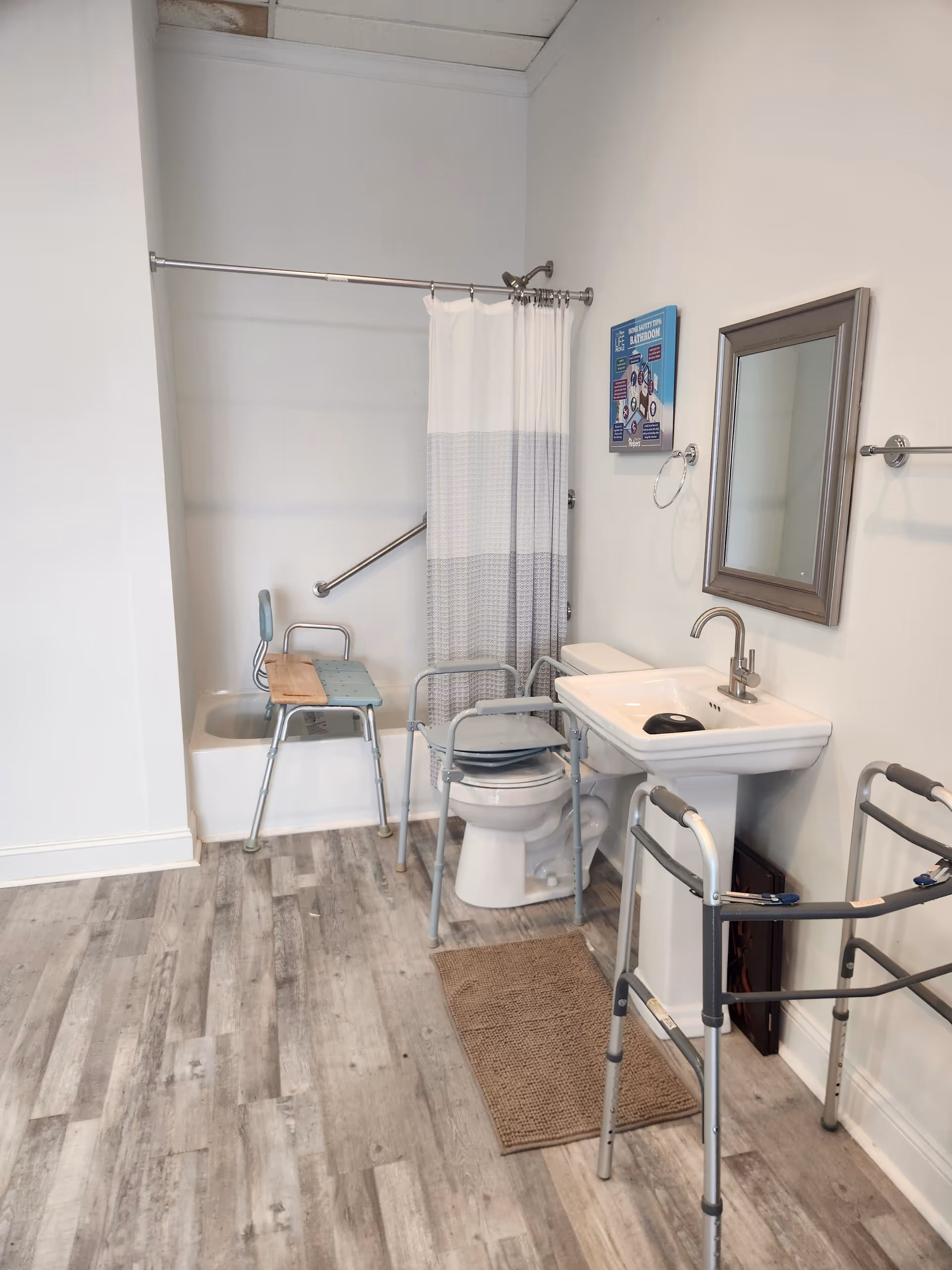 Accessible bathroom featuring shower curtain, shower chair, walker, sink, and mirror.