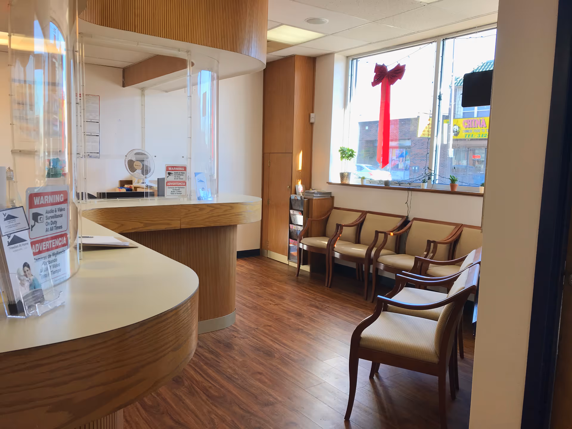 Reception area with curved wood desk, waiting chairs by window and holiday red ribbon decor