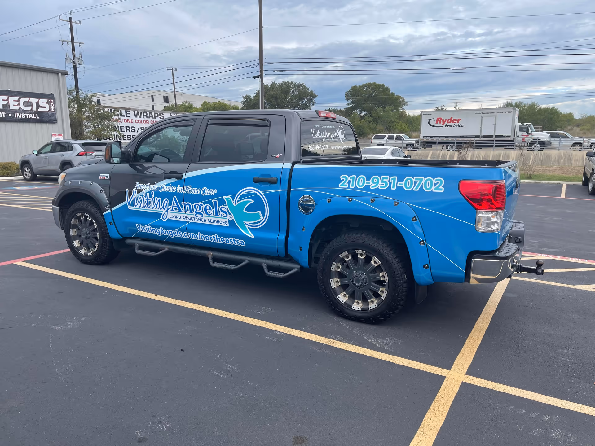 Blue pickup truck with Visiting Angels branding parked in a parking lot