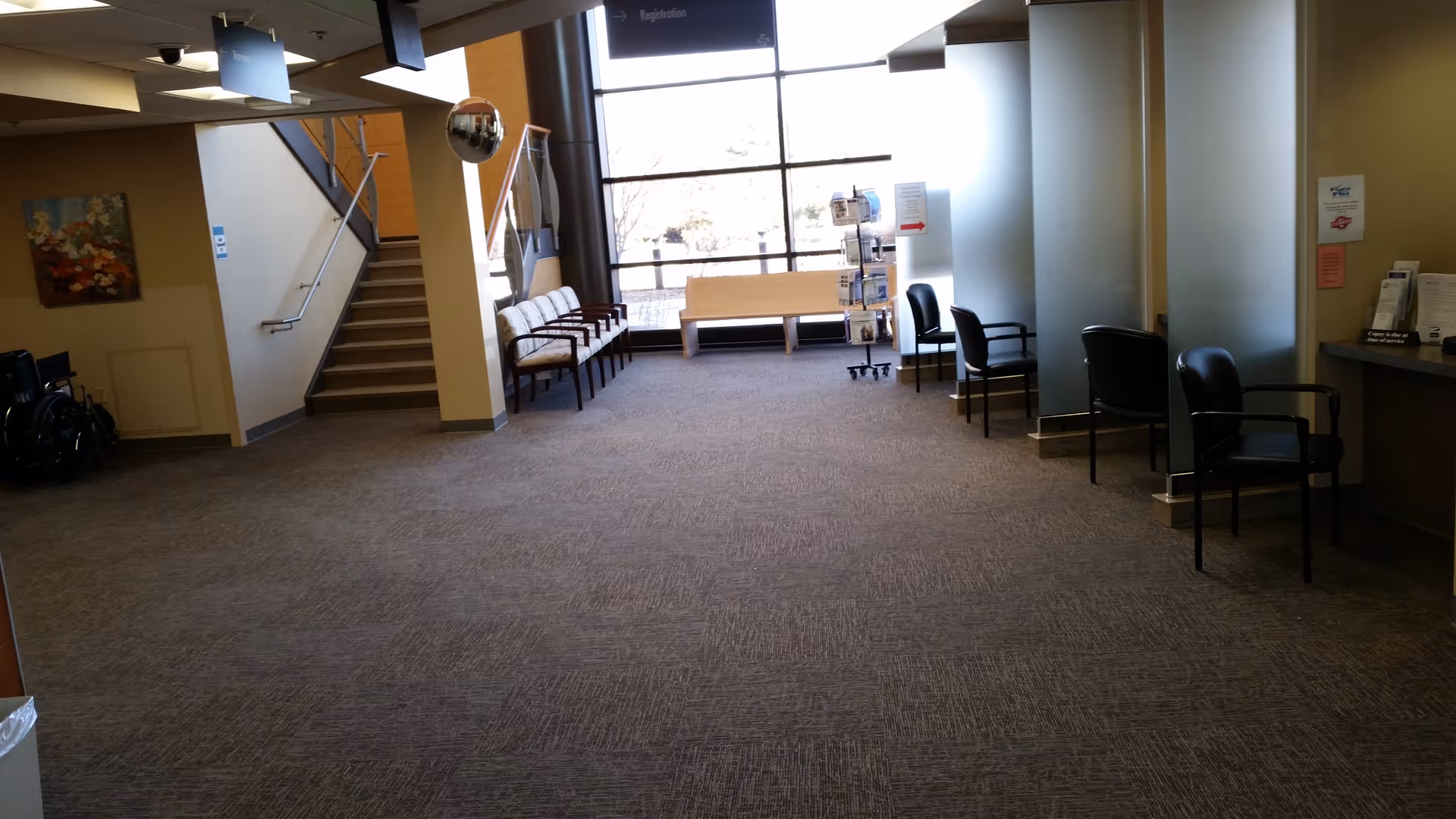 Spacious interior lobby with chairs along the wall and a staircase near seating.
