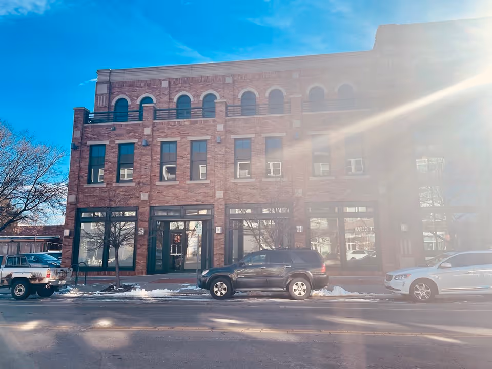 Brick, front-facing senior facility with large windows, parked cars, and light snow.