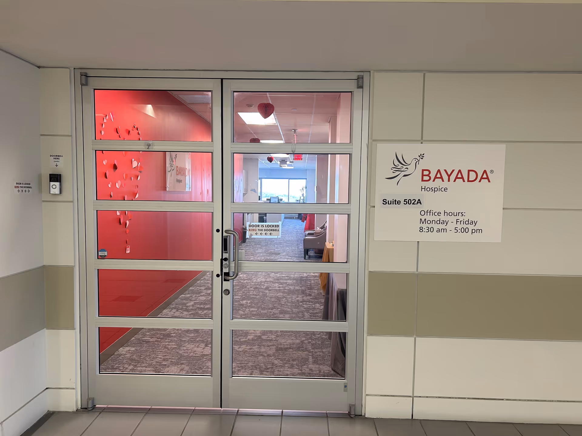 Glass double doors open to a BAYADA Hospice hallway with a sign.