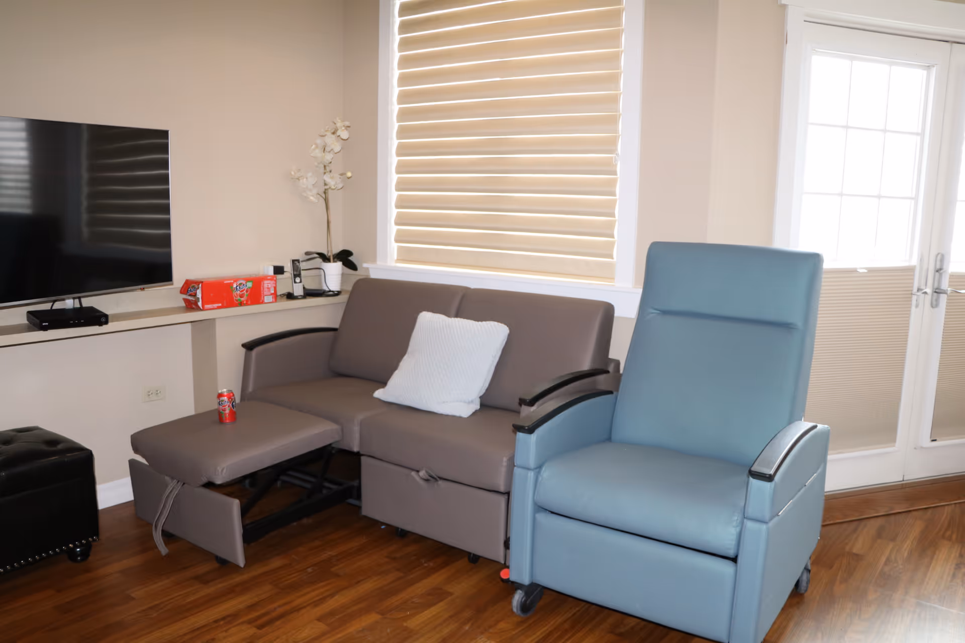 Cozy living room with a gray sofa, blue recliner, TV, and wood floors.