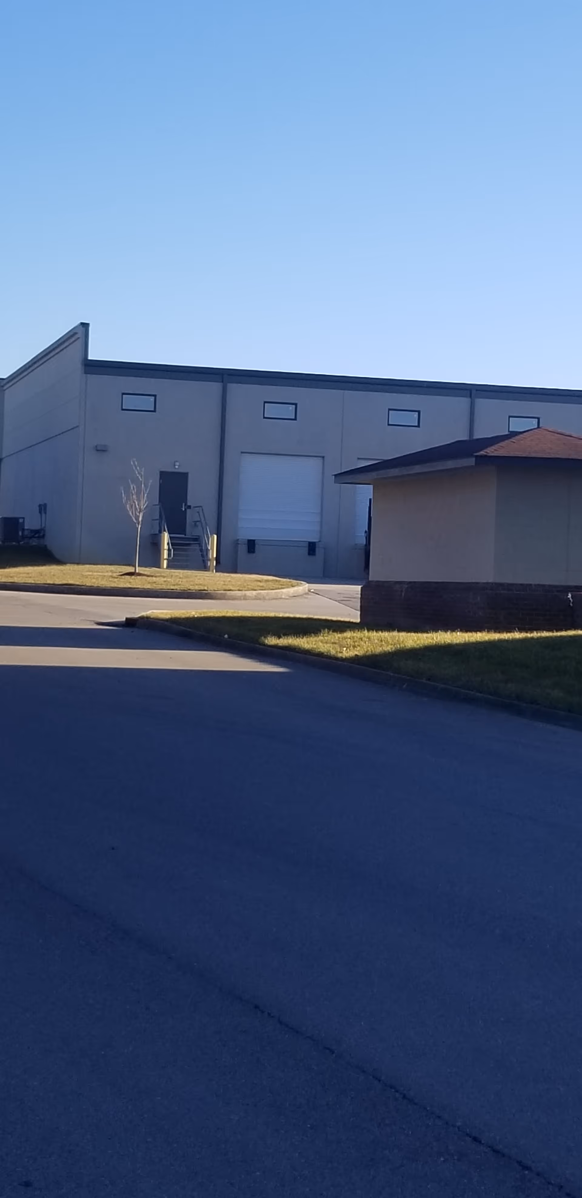 Exterior view of a large industrial-style building with loading dock and driveway.