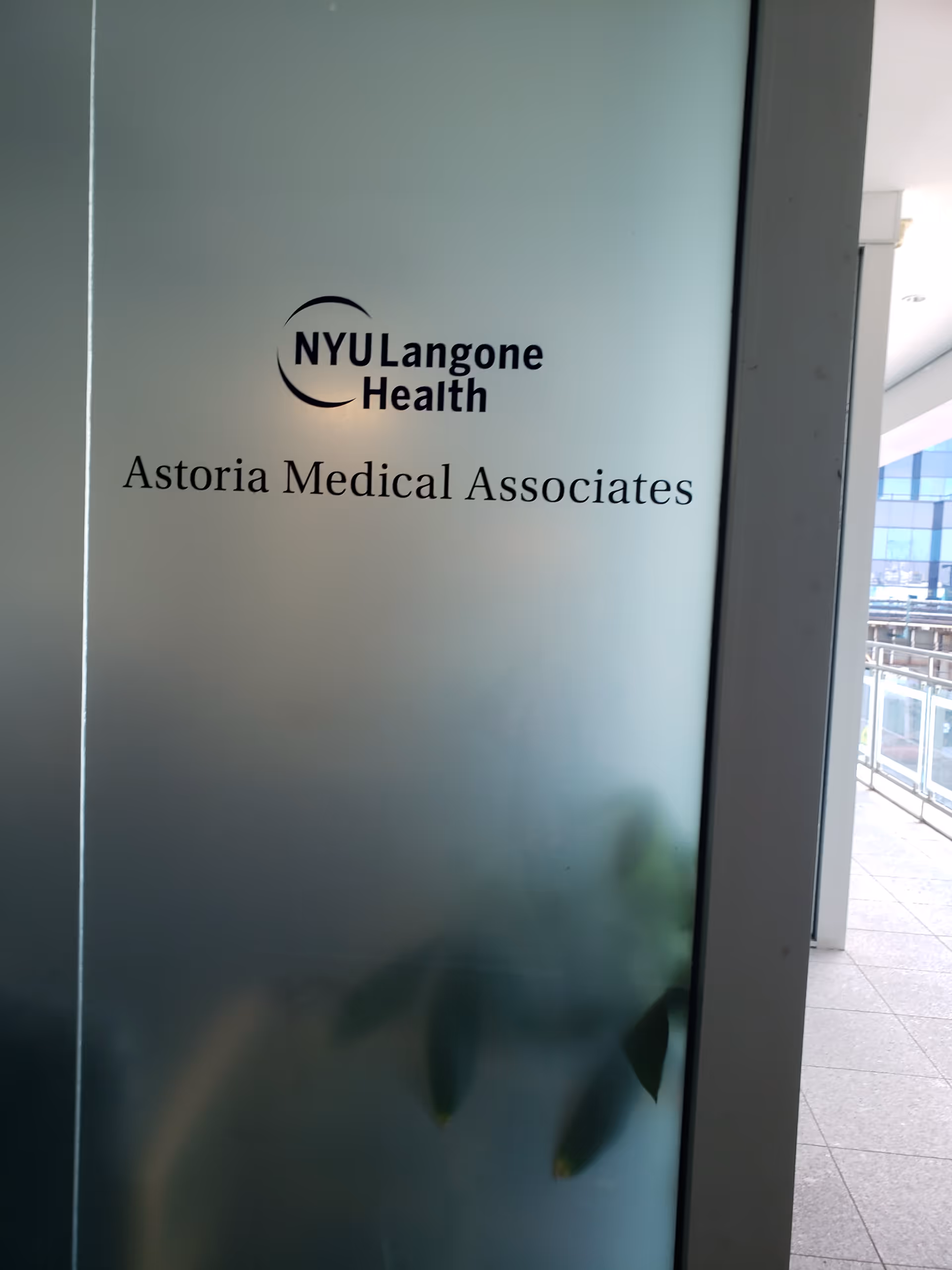 Frosted glass panel displays NYU Langone Health Astoria Medical Associates signage.