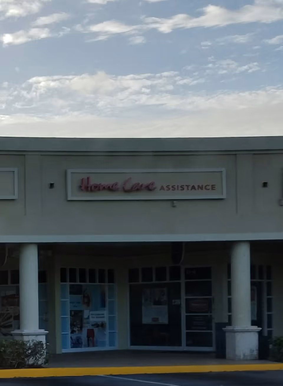 Exterior view of a senior home care facility entrance with sign and columns.