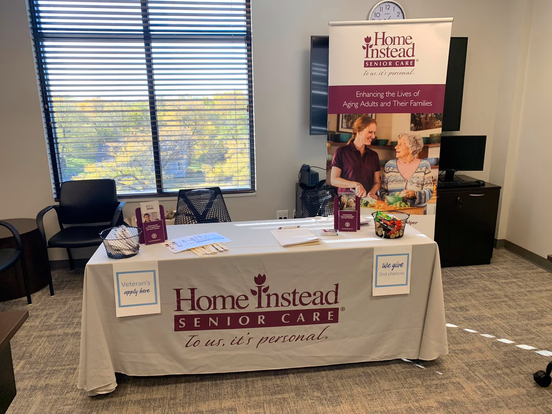 Indoor setup shows a Home Instead promotional table with banner and brochures.