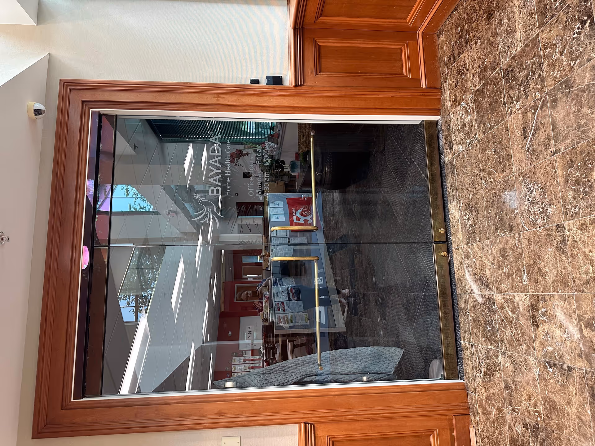 Entrance to BAYADA Hospice with glass doors, wooden frame, and marble flooring.