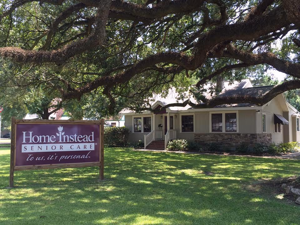 Front view of a Home Instead senior care building with sign and trees