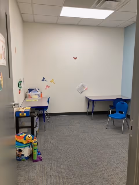 Small activity room with blue chairs, tables, and children's toys.
