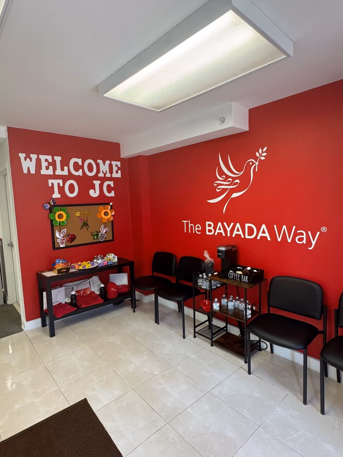 Red-walled lobby with chairs, a coffee bar, and The BAYADA Way signage.