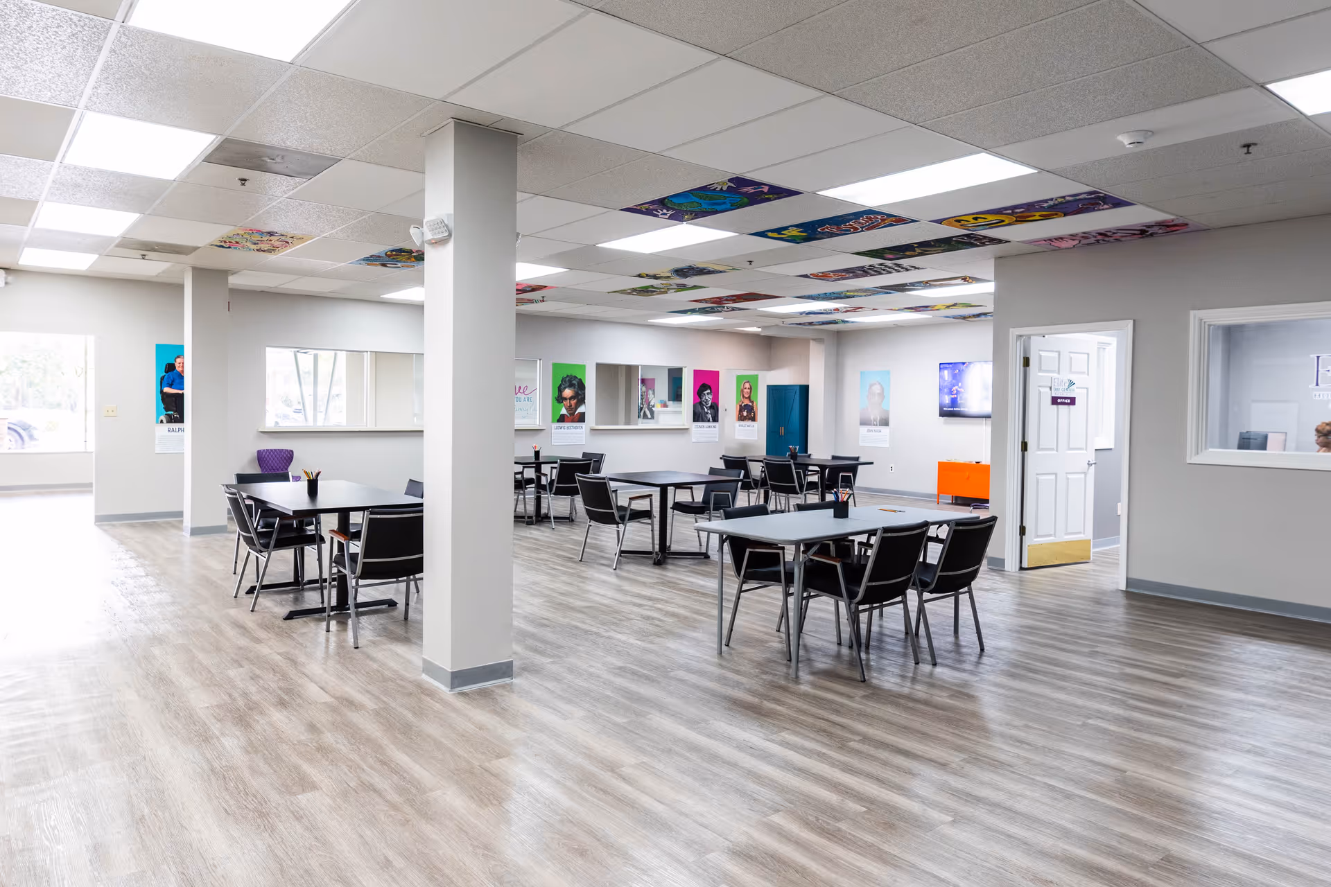 A spacious, well-lit common area with multiple tables and chairs in a senior facility.