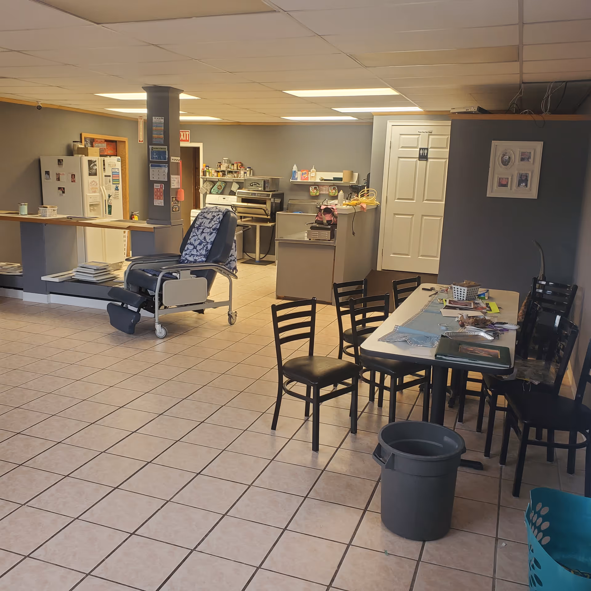 Interior common area with kitchen, a wheeled chair, and a dining table.