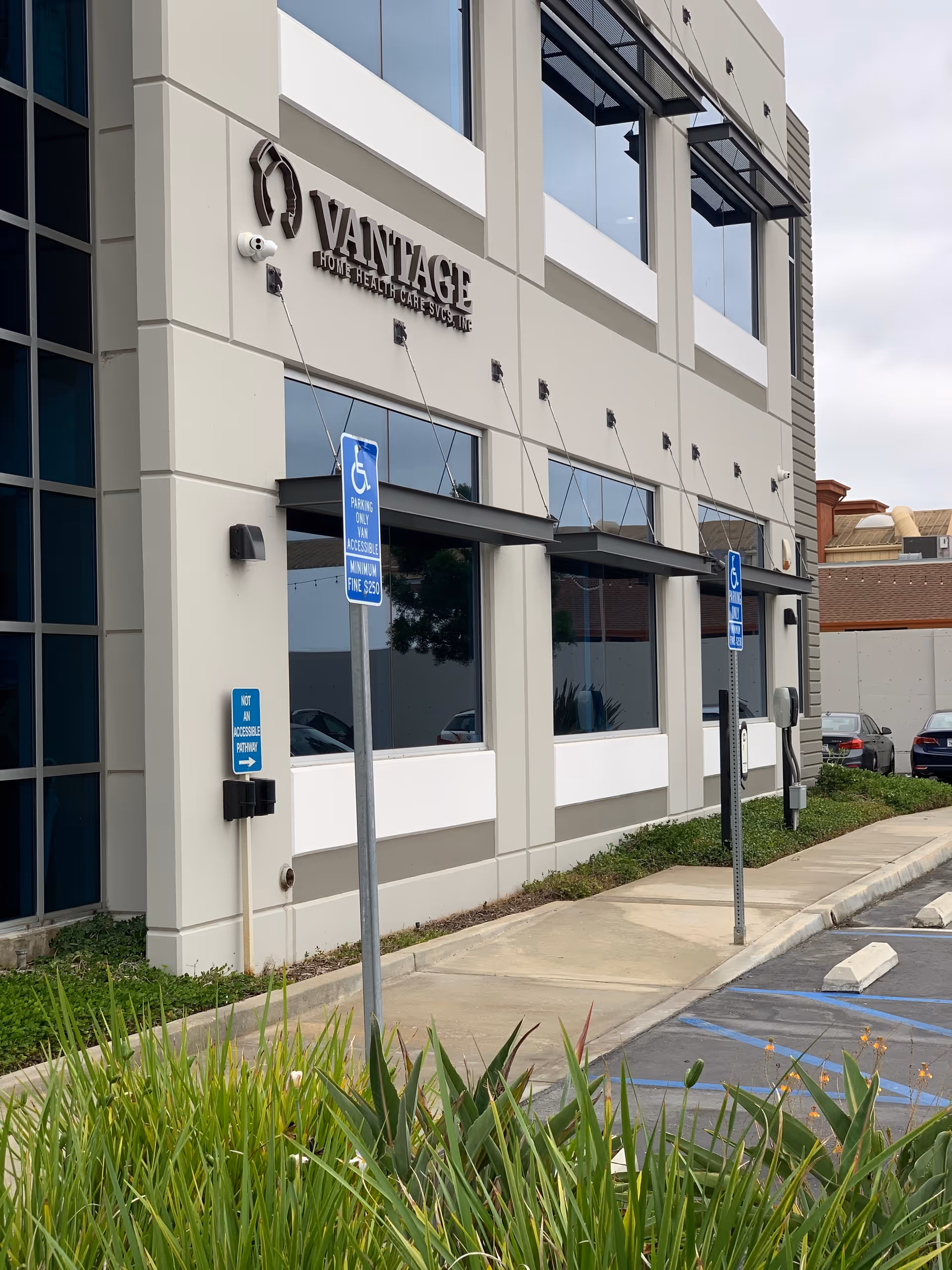 Vantage Home Health Care Services building exterior with wheelchair parking signs and shrubs.