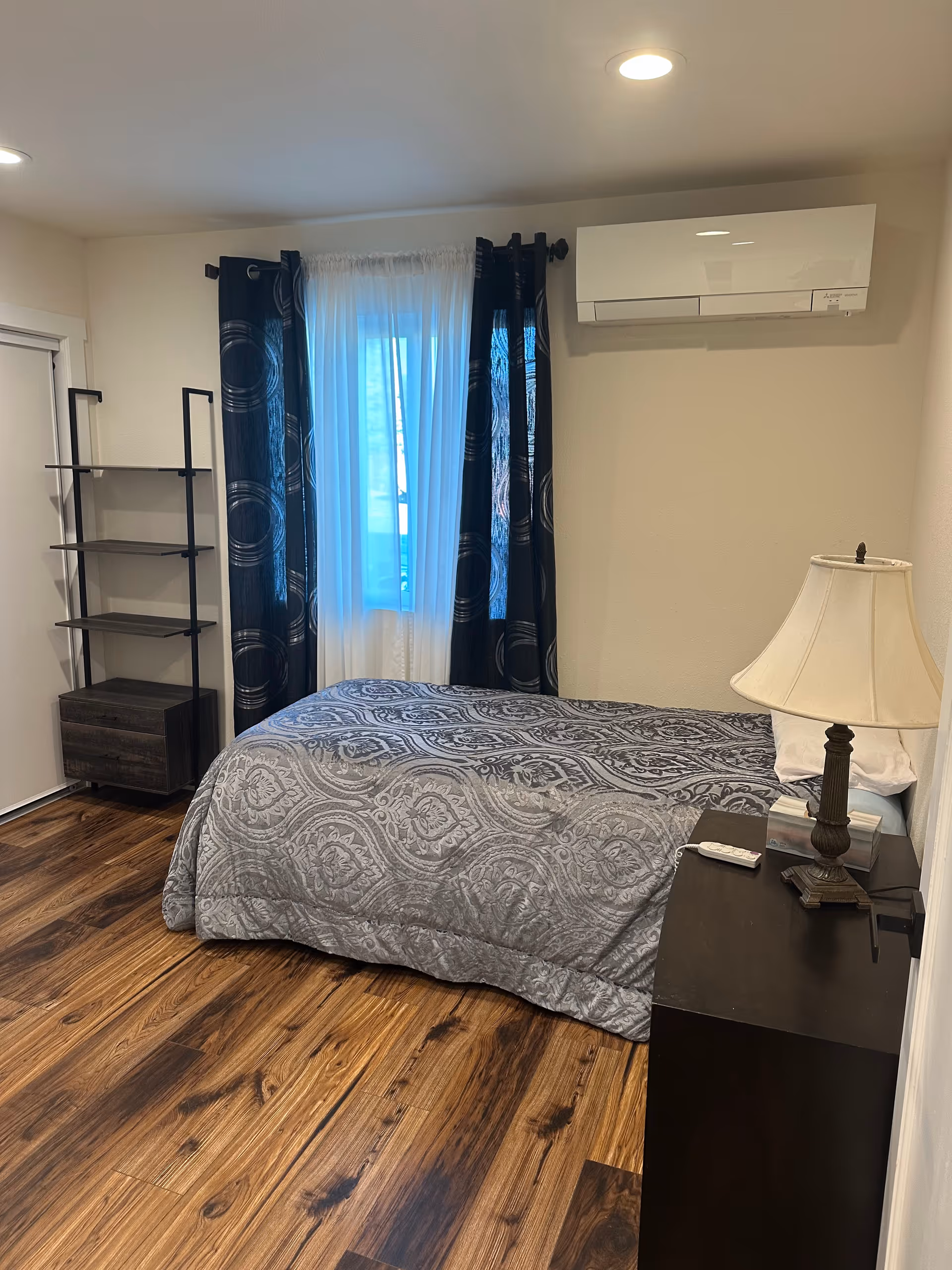 A furnished bedroom in a senior living facility with bed and window.