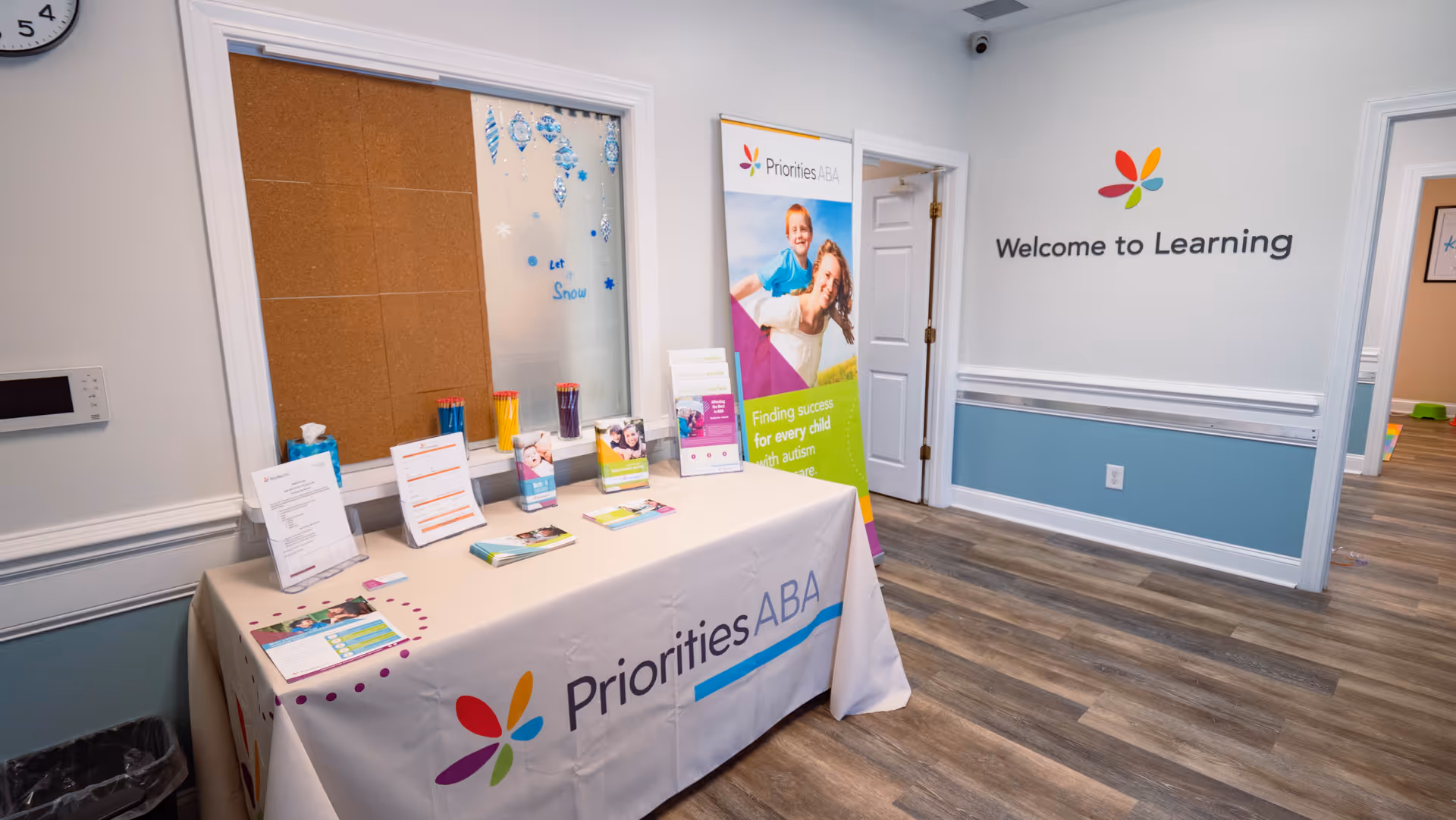 Interior reception area with a Priorities ABA table, promotional materials, and Welcome to Learning sign