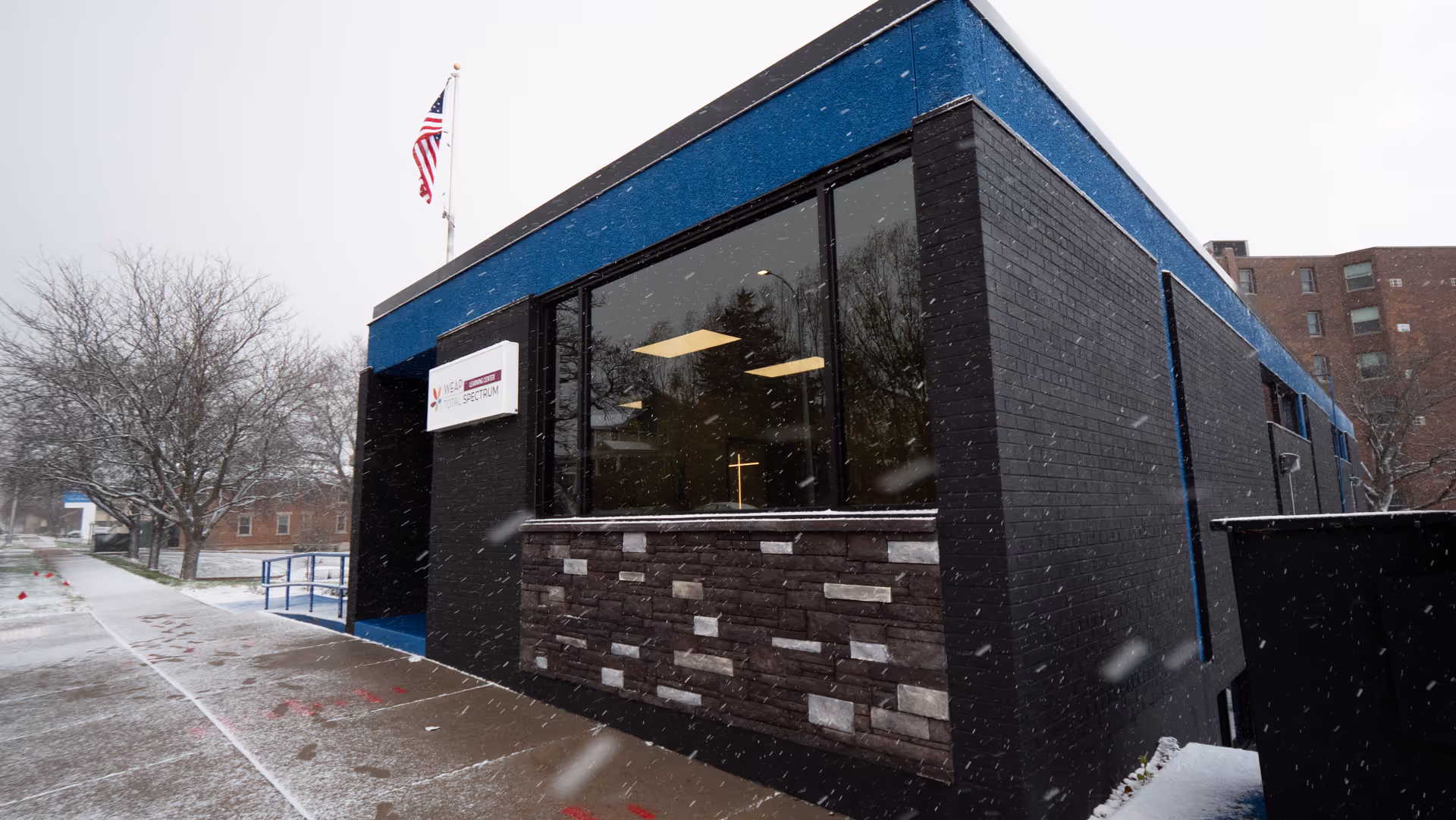 Exterior view of a dark brick building with large windows and snow.