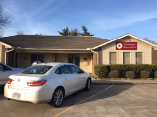 Exterior view of Enhabit Home Health building with parked cars and shrubs