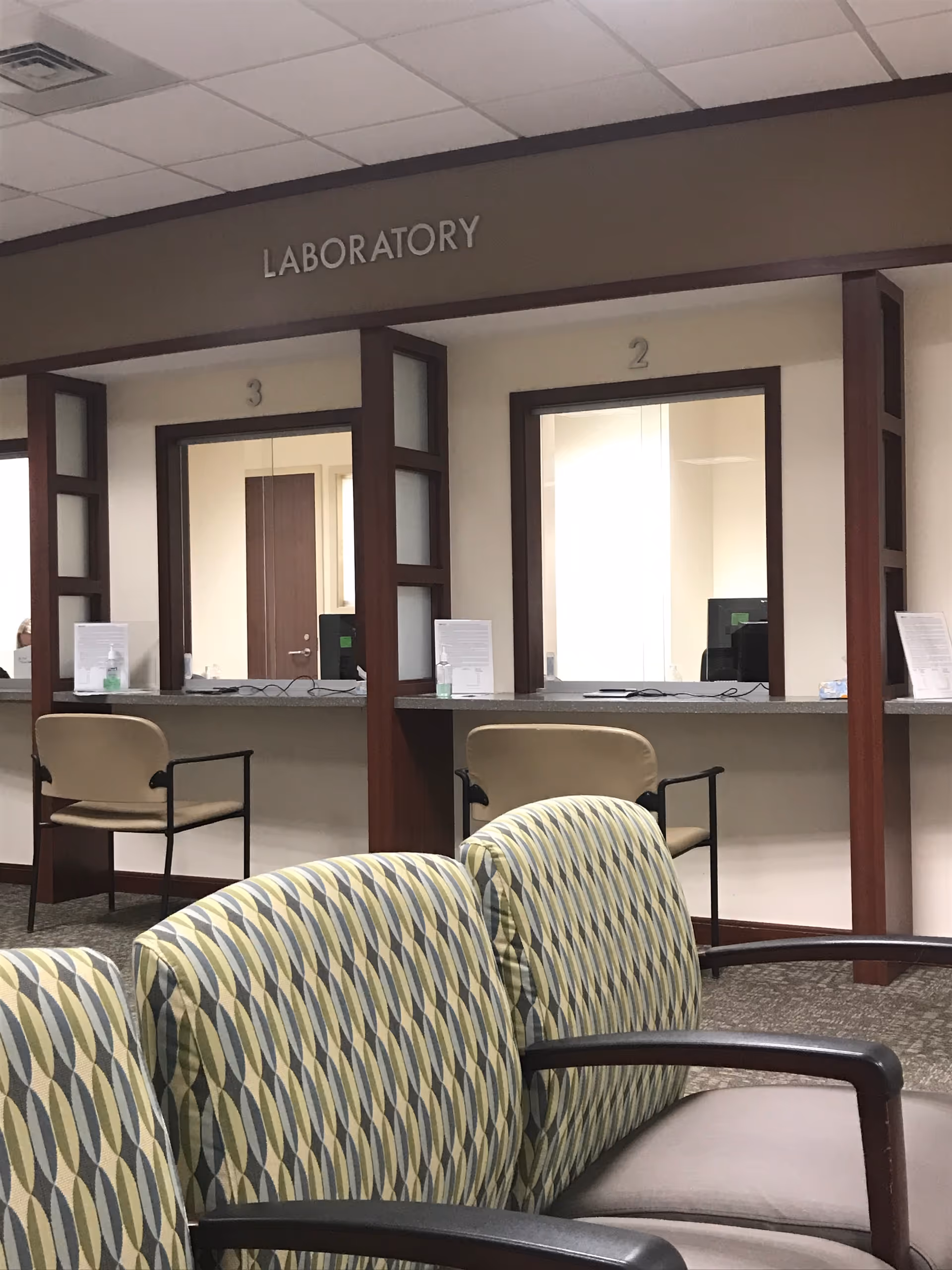 Interior view of a laboratory reception area with numbered windows and seating.