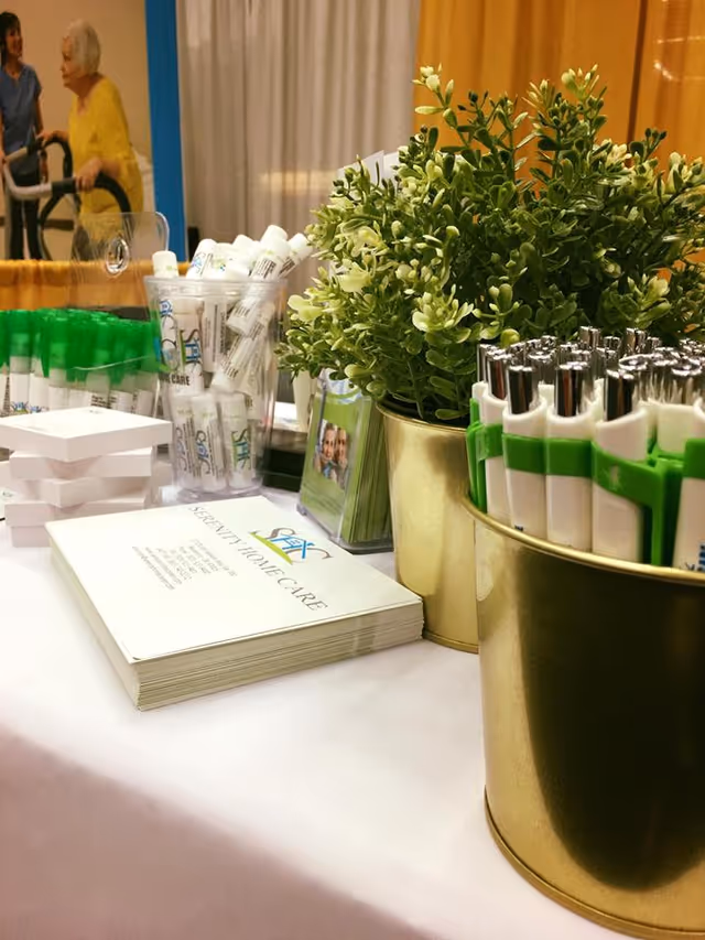 Promotional table with brochures, pens, and plants inside a senior care facility lobby.