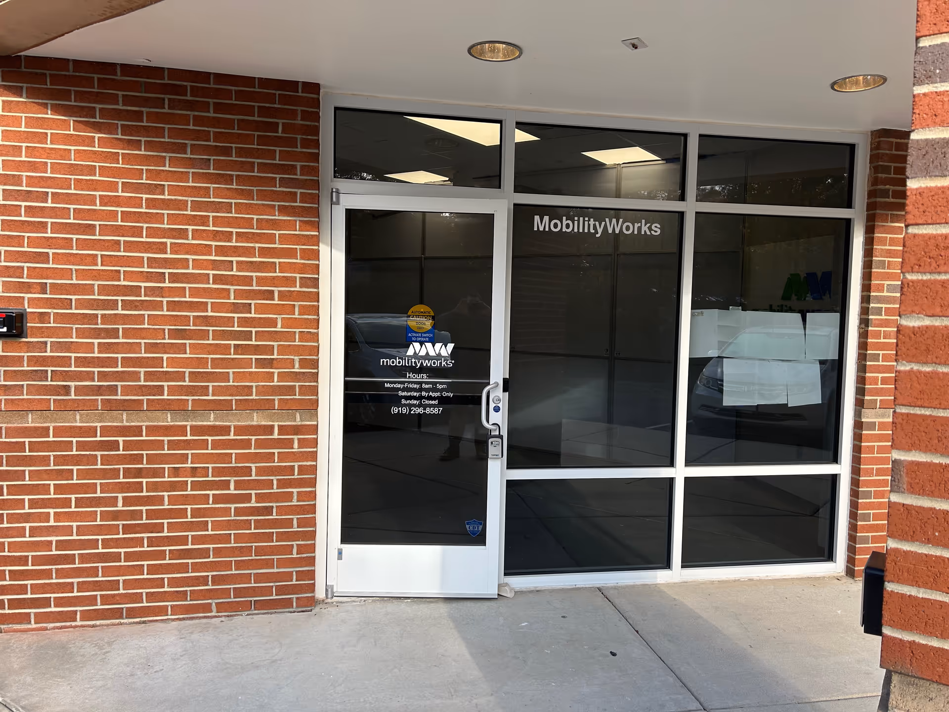 Brick building entrance with glass doors labeled MobilityWorks and a concrete sidewalk.