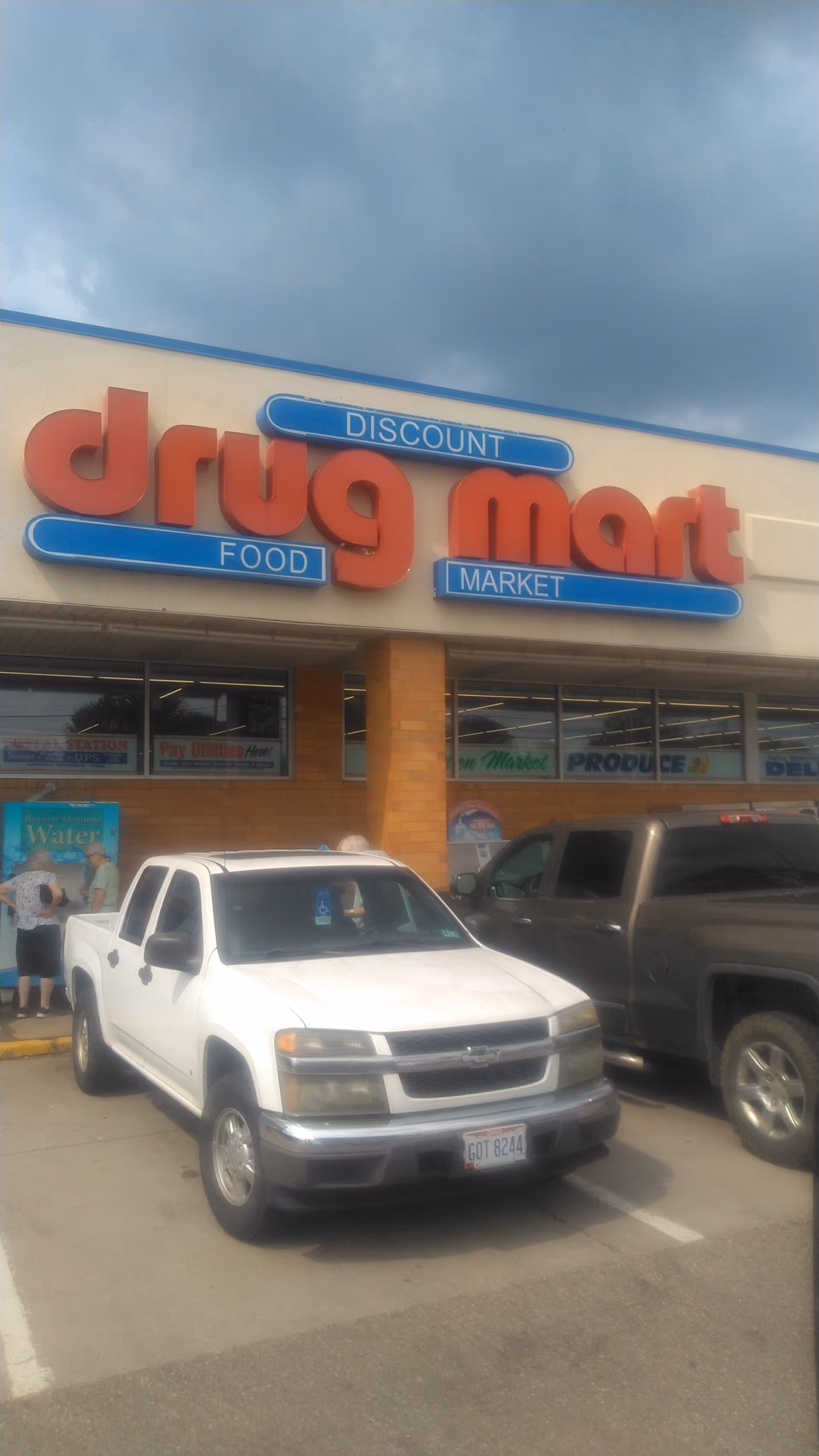 Exterior view of Discount Drug Mart storefront with a white pickup in a parking lot.