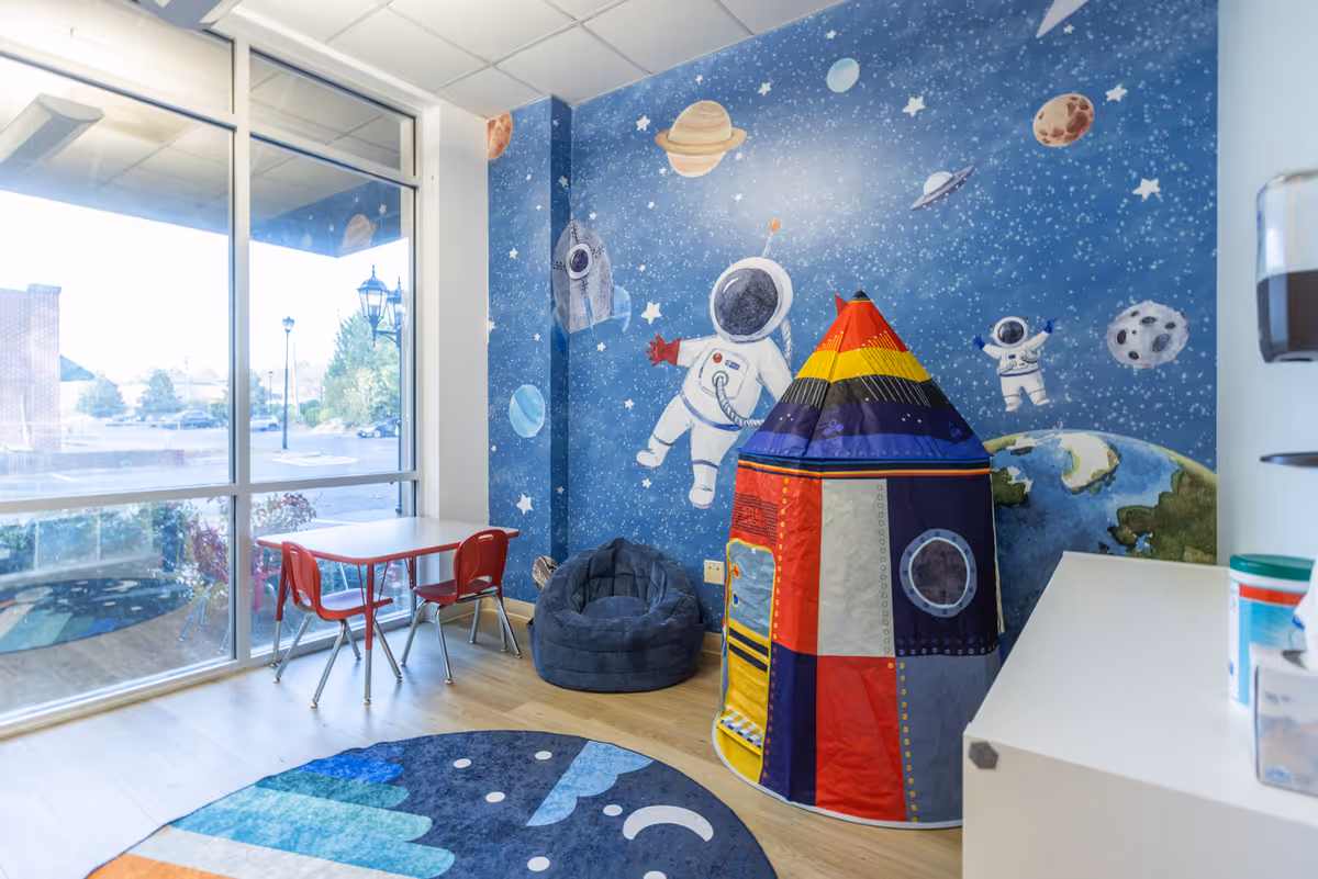 Colorful space-themed children's play area with a tent, bean bag, and small table.