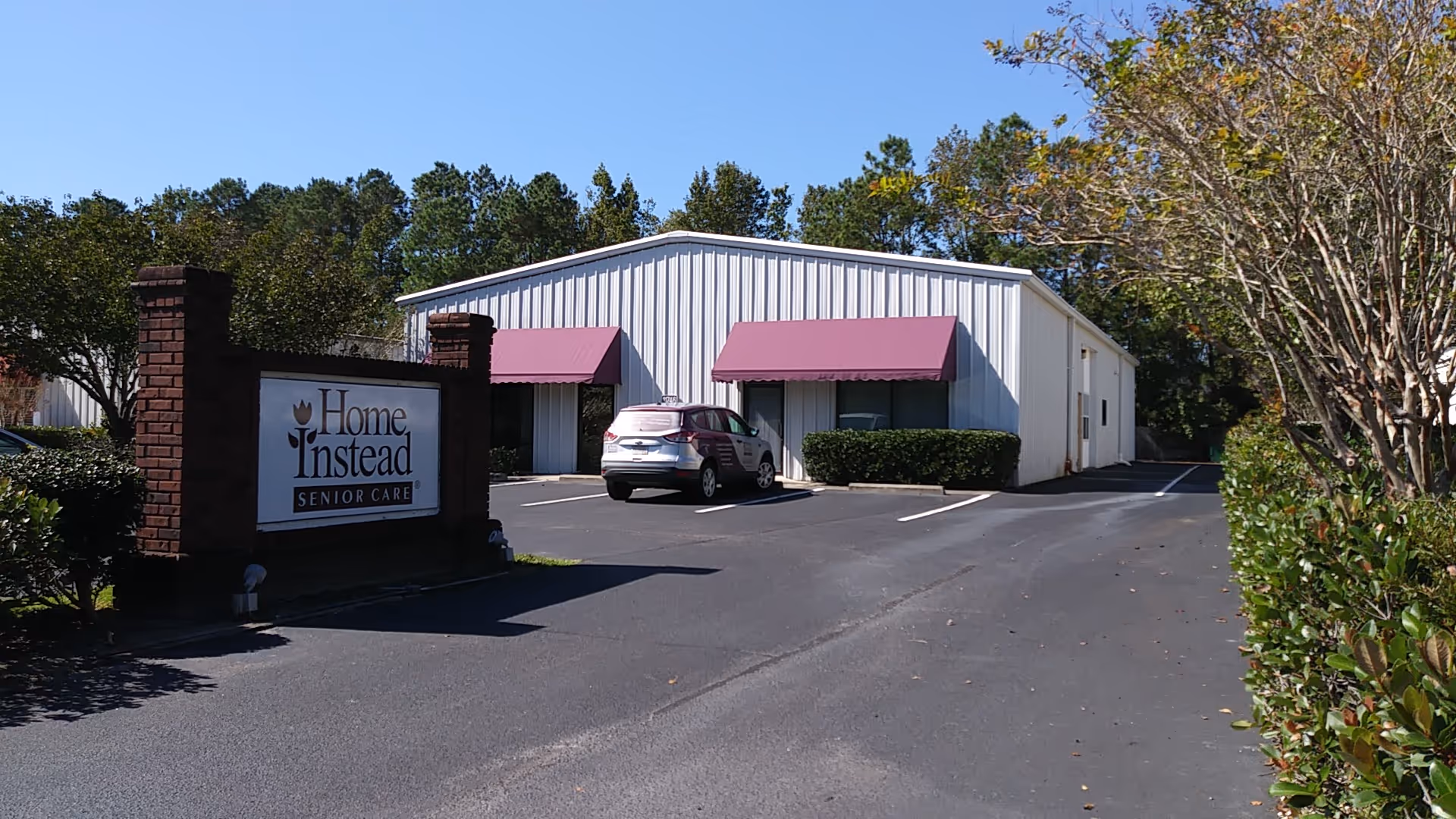 Exterior view of a Home Instead senior care building with a sign and parking lot.